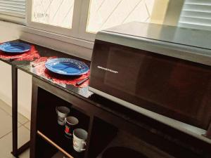 un horno microondas con platos y tazas sobre una mesa en Casa Petit - Banheiro Exclusivo en Natal