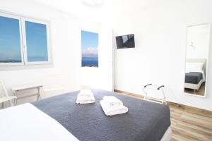 een witte slaapkamer met een bed met twee handdoeken erop bij Crystal View Mykonos in Mykonos-stad