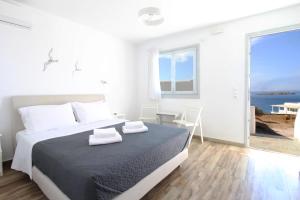 een witte slaapkamer met een bed en uitzicht op de oceaan bij Crystal View Mykonos in Mykonos-stad