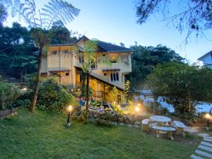 una casa con mesas y sillas en el patio en Highlanders Garden Guesthouse at Arundina Cameron Highlands en Cameron Highlands