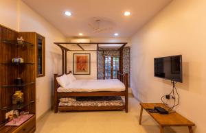 um quarto com uma cama e uma televisão em SaffronStays Birdsong, Madh - pet-friendly villa at Madh Island em Mumbai