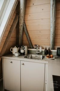 een keuken met een wastafel en een houten plafond bij Guesthouse in het Voorhuys in Doesburg