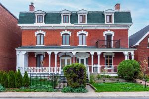 uma grande casa de tijolos vermelhos com um telhado verde em Centennial 6-Bedroom Waterfront Palace Sleeps 14 em Montreal