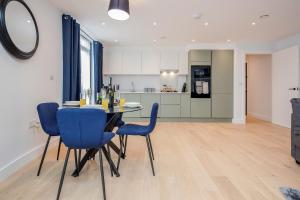 cocina y comedor con mesa y sillas azules en Watford Cassio Deluxe - Modernview Serviced Accommodation en Watford