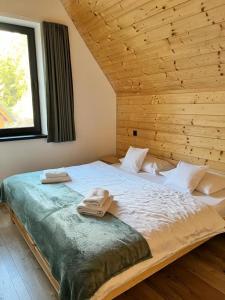 1 dormitorio con 1 cama grande y pared de madera en Chata Demian en Demanovska Dolina