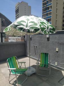 twee stoelen en een paraplu op het dak bij Suítes/Studios Privados Copacabana in Rio de Janeiro