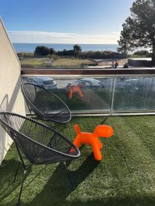 un balcón con una silla y un juguete naranja en la hierba en Studio vue mer avec terrasse et accès plage en Carnac