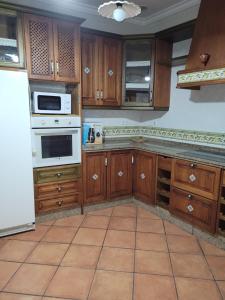 a kitchen with wooden cabinets and a white appliance at Habitaciones La Flamenka in Ronda