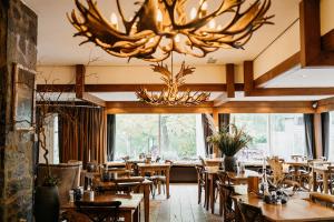 een restaurant met houten tafels en stoelen en een kroonluchter bij Badhotel Rockanje in Rockanje