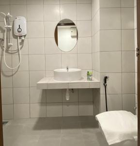 La salle de bains est pourvue d'un lavabo et d'un miroir. dans l'établissement Capital O 90756 Cara Hulu Hotel, à Kampong Morten