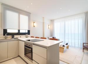 een keuken met witte apparatuur en een woonkamer bij LIV Mackenzie Beach Suites Larnaca ADULTS ONLY in Larnaka