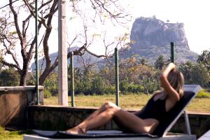 una mujer sentada en una silla con una montaña en el fondo en Royal Rock Sigiriya, en Sigiriya