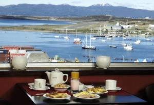 einen Tisch mit Tellern und Blick auf den Hafen in der Unterkunft MIL810 Ushuaia Hotel in Ushuaia