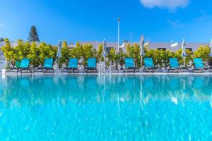 a row of blue chairs in a swimming pool at Rosamar Apartamentos in Puerto del Carmen