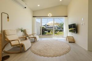 a living room with chairs and a large window at Panpo HyunStay in Jeju