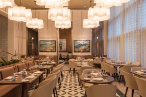 una sala da pranzo con tavoli, sedie e lampadari a braccio di Hotel Beaux Arts, Autograph Collection a Miami