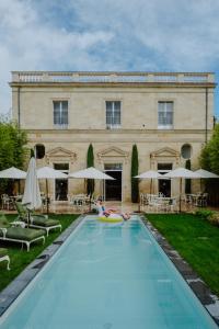 una persona nadando en una piscina frente a un edificio en Hôtel Maison Pavlov en Le Bouscat