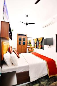 una camera da letto con un grande letto con lenzuola bianche e cuscini rossi di The Beach Cottage Kappad a Kozhikode