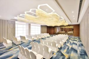 uma sala de conferências com cadeiras brancas e um lustre em Fairfield by Marriott Indore em Indore