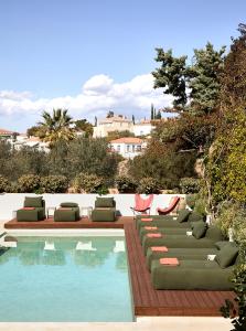 una piscina con tumbonas y sillas junto a una piscina en Yayaki Spetses, en Spetses