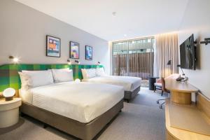 ウェリビーにあるHoliday Inn Werribee, an IHG Hotelのベッド2台とデスクが備わるホテルルームです。