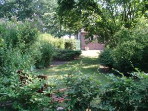 un jardin avec des buissons et des arbres et un bâtiment dans l'établissement De Erfdijk, à Herpen