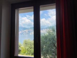 une fenêtre avec vue sur l'eau dans l'établissement Villa Pifferi, à Malcesine