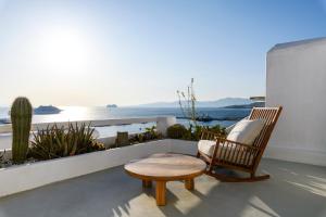 un fauteuil et un tabouret sur un balcon avec vue sur l'océan dans l'établissement She Mykonos - The Residency, à Mykonos