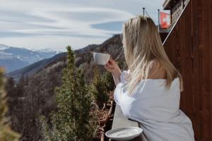 kobieta trzymająca filiżankę kawy na balkonie w obiekcie Boutique Hotel Panorama w mieście Crans-Montana