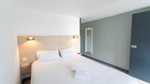 1 dormitorio con 1 cama blanca grande y ventana en Hotel Inn Design La Rochelle, en La Rochelle