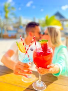 Uma mulher a beber dois cocktails com um homem. em Curacao Avila Beach Hotel em Willemstad