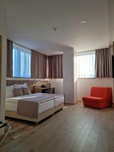 - une chambre avec un grand lit et une chaise rouge dans l'établissement Hotel Emerald, à Mostar