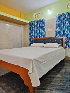 a large bed in a room with blue curtains at Jagannatha Guest House in Puri