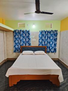 a bedroom with a large bed with blue curtains at Jagannatha Guest House in Puri