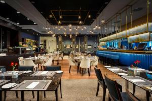 a restaurant with tables and chairs and a bar at Hilton Garden Inn Krakow Airport in Kraków