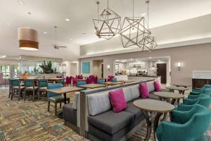 een lobby met een bank en tafels en stoelen bij Homewood Suites Fort Myers Airport - FGCU in Fort Myers