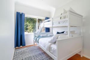 um quarto branco com um beliche branco e uma janela em The Farmer s Retreat em Kiama