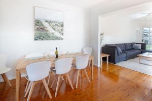 uma sala de jantar e sala de estar com uma mesa de madeira e cadeiras brancas em The Farmer s Retreat em Kiama