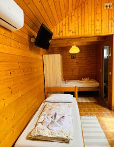 1 dormitorio con 1 cama en una habitación de madera en Babett Vendégház en Zánka