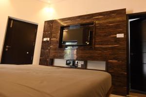 1 dormitorio con 1 cama y TV en la pared en Melody Inn Luxury Home Stay, en Yercaud