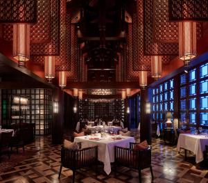 une salle à manger avec des tables, des chaises et des lustres dans l'établissement The Ritz-Carlton, Langkawi, à Pantai Kok