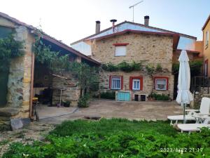 uma casa de pedra com um pátio e um guarda-chuva em El Zoela em Zamora