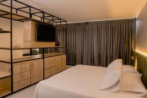 a bedroom with a white bed and a television at Hotel Principe in Tuluá