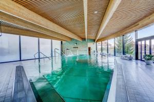 uma piscina interior com água verde num edifício em Hôtel Cailler & Bains de la Gruyère em Charmey