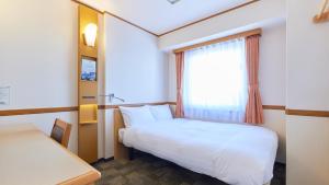 Habitación pequeña con cama y ventana en Toyoko Inn Hokkaido Hakodate Ekimae Daimon, en Hakodate