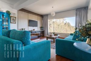 una sala de estar con muebles azules y una gran ventana. en Mansão Sky View Vista Panorâmica Luxo na Serra, en Rancho Queimado