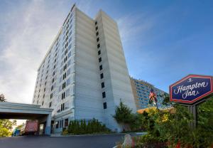 Un grand bâtiment blanc avec un panneau devant. dans l'établissement Hampton Inn NY-JFK, à Queens