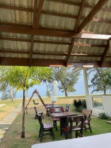 una mesa de picnic y sillas bajo un pabellón con parque infantil en DamaiiKu en Cherating