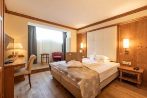 een hotelkamer met een bed en een bureau bij Alpin & Vital Hotel La Perla in Ortisei