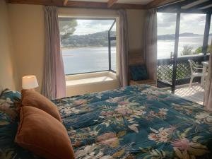 1 dormitorio con cama y vistas al agua en The Retreat Bay of Islands, en Paihia